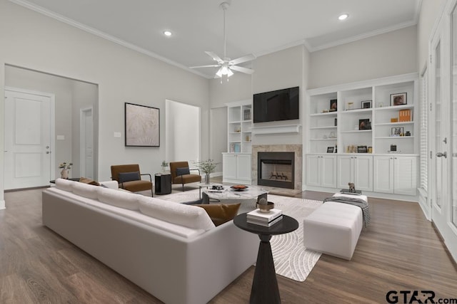 living room featuring hardwood / wood-style flooring, ceiling fan, ornamental molding, and a tiled fireplace