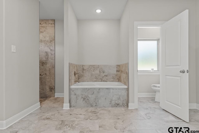 bathroom featuring a relaxing tiled tub and toilet