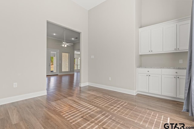 empty room with ceiling fan, crown molding, and light wood-type flooring