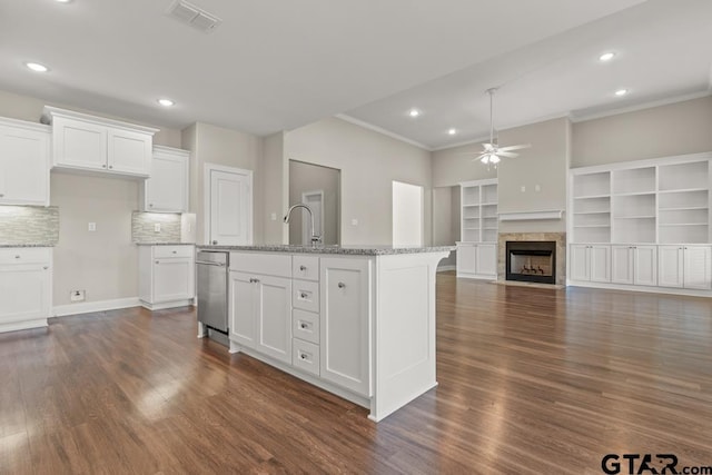 kitchen featuring tasteful backsplash, a center island with sink, white cabinetry, and ceiling fan