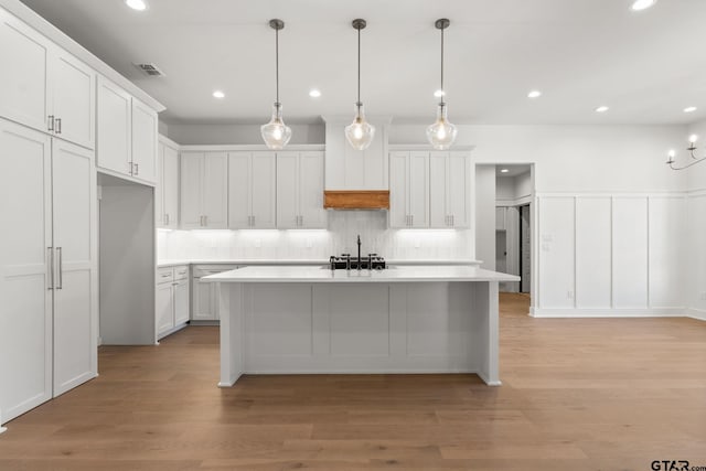 kitchen with white cabinetry, pendant lighting, light hardwood / wood-style flooring, and a center island