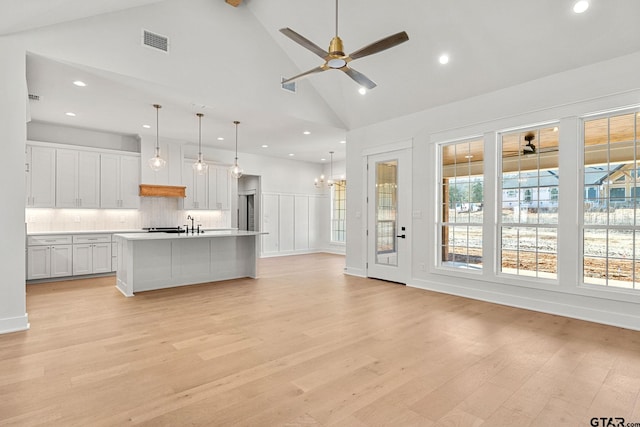 kitchen with white cabinetry, pendant lighting, a center island with sink, and ceiling fan with notable chandelier