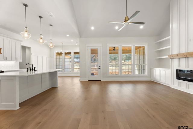 kitchen with ceiling fan, decorative light fixtures, vaulted ceiling, and white cabinets