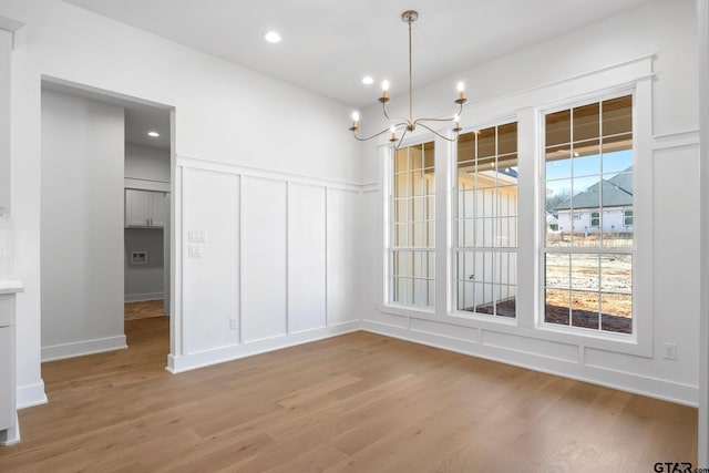 unfurnished dining area featuring light hardwood / wood-style flooring, a wealth of natural light, and a chandelier