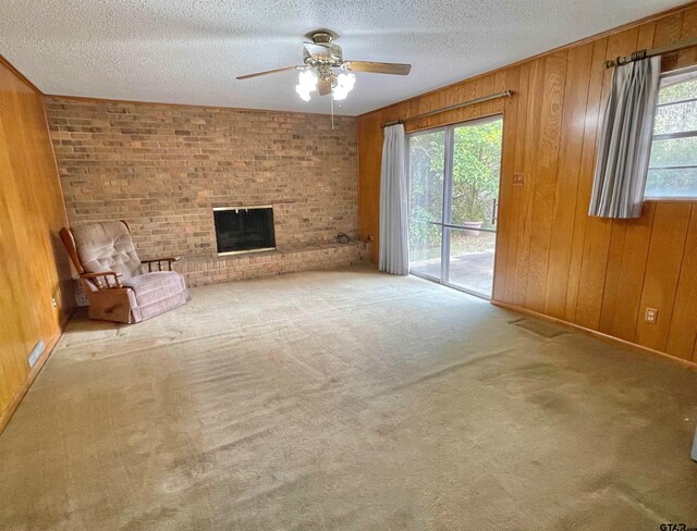 unfurnished living room with carpet flooring, a wealth of natural light, and wooden walls