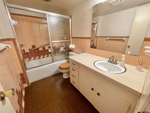 full bathroom featuring tile walls, vanity, bath / shower combo with glass door, toilet, and parquet floors