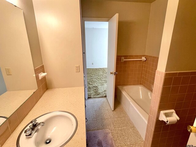 bathroom with vanity, a bathtub, and tile walls