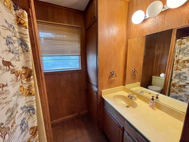 bathroom with toilet, vanity, and wooden walls