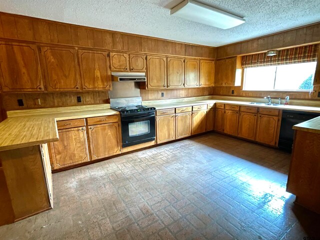 kitchen featuring black appliances, a textured ceiling, sink, and wooden walls