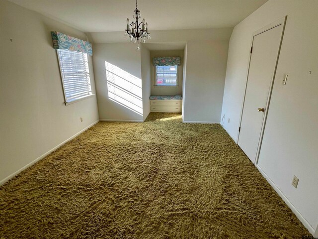 unfurnished room featuring a chandelier and carpet