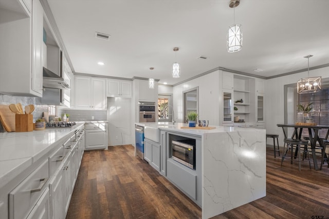 kitchen featuring stainless steel appliances, a sink, dark wood-style floors, white cabinets, and ornamental molding