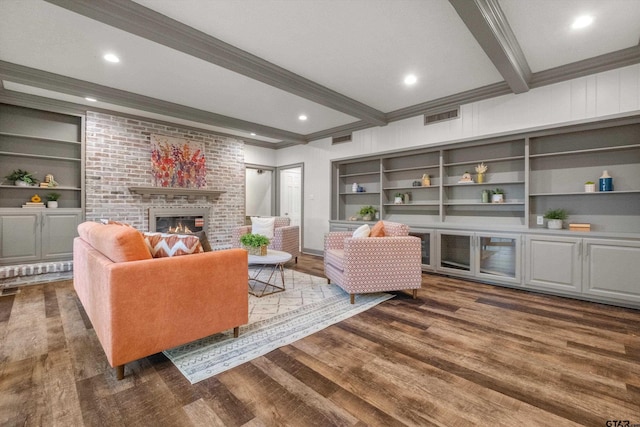 living area with beamed ceiling, a fireplace, wood finished floors, built in features, and ornamental molding