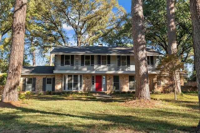 colonial inspired home with brick siding, a front lawn, and a balcony