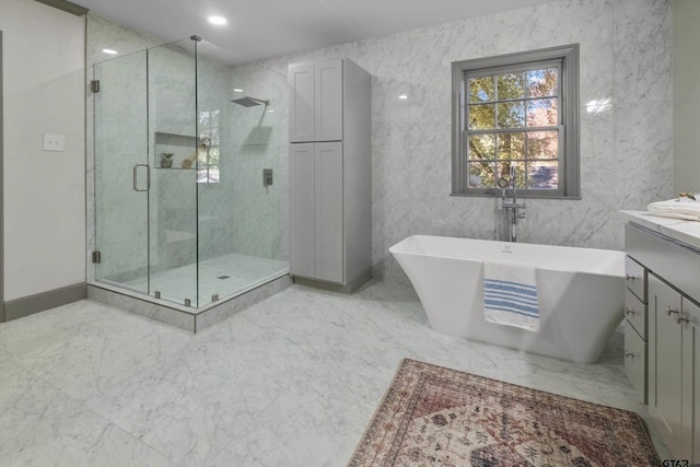 full bath with a stall shower, vanity, a freestanding tub, and marble finish flooring