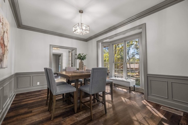 dining area featuring a decorative wall, a chandelier, dark wood-type flooring, wainscoting, and ornamental molding