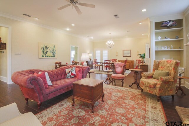 living room featuring built in shelves, ceiling fan with notable chandelier, hardwood / wood-style flooring, and crown molding