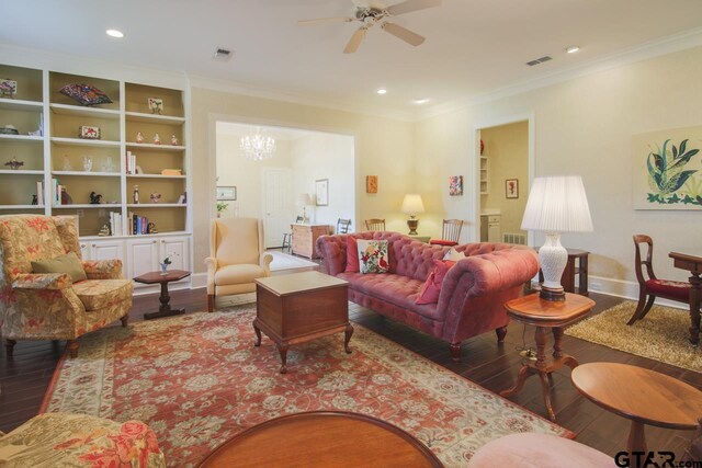 living room featuring built in shelves, ceiling fan with notable chandelier, crown molding, and hardwood / wood-style floors