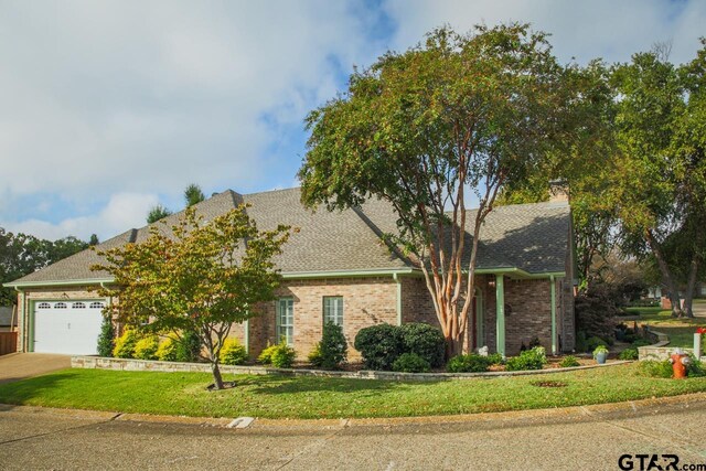 view of front of house featuring concrete driveway, roof with shingles, an attached garage, a front lawn, and brick siding