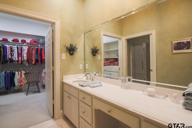 bathroom with tile patterned flooring, a walk in closet, and vanity