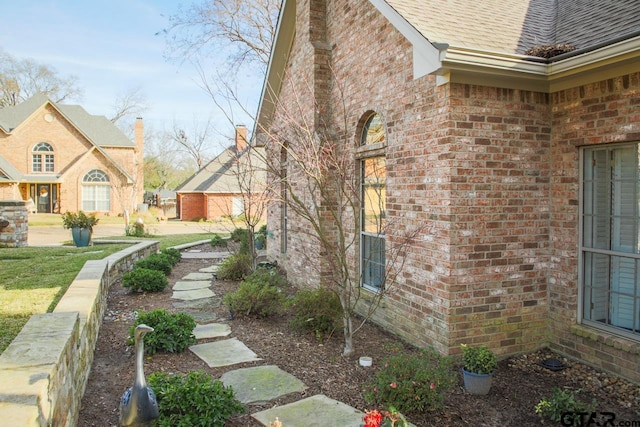 view of side of property with roof with shingles and brick siding