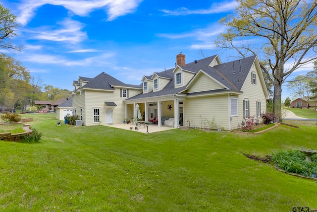 rear view of property featuring a garage, a lawn, and a patio area