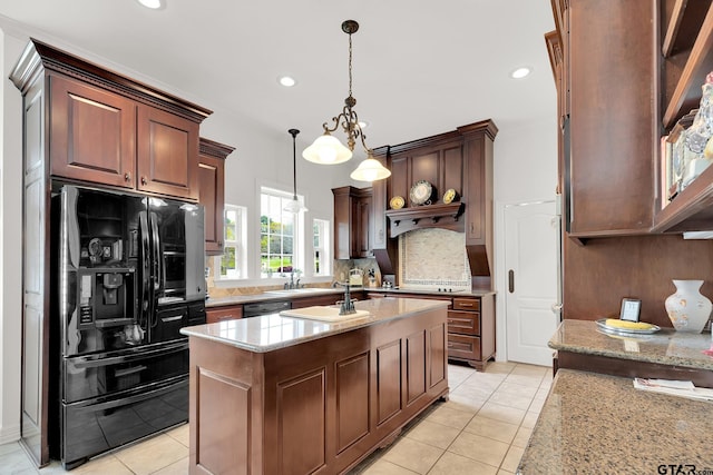 kitchen with hanging light fixtures, light tile patterned flooring, black appliances, and light stone counters