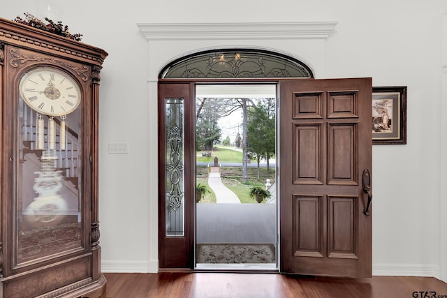 entryway with ornamental molding and dark hardwood / wood-style flooring