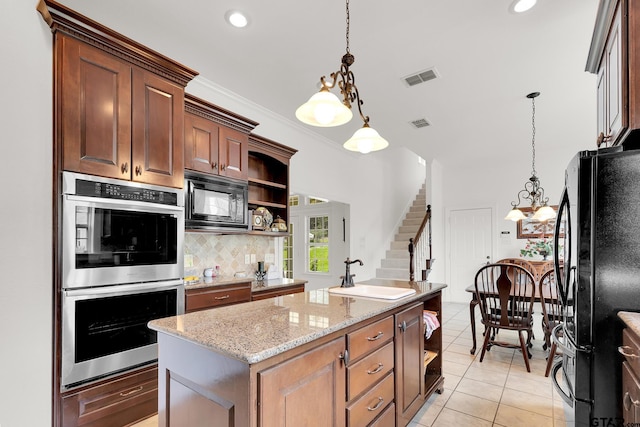 kitchen featuring pendant lighting, black appliances, light tile patterned flooring, and an island with sink