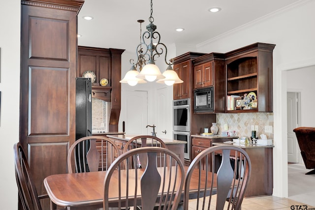 kitchen with hanging light fixtures, black appliances, a chandelier, light tile patterned floors, and ornamental molding