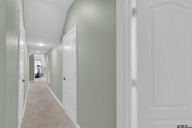 hallway with light carpet and lofted ceiling