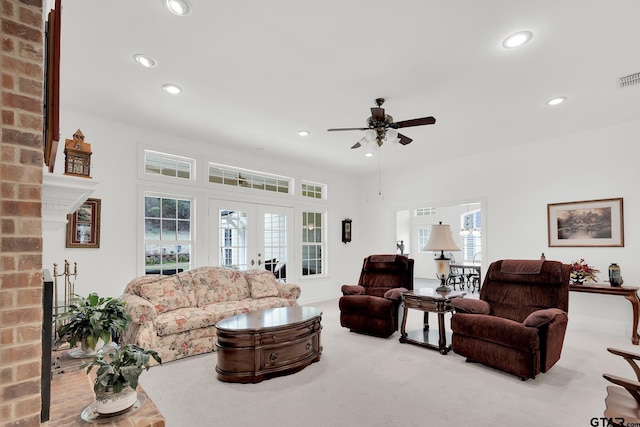 living room featuring a wealth of natural light, french doors, ceiling fan, and a fireplace