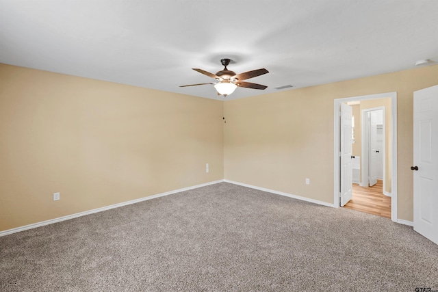 empty room with visible vents, carpet, ceiling fan, and baseboards