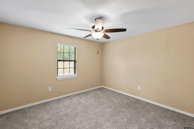 carpeted spare room featuring ceiling fan and baseboards
