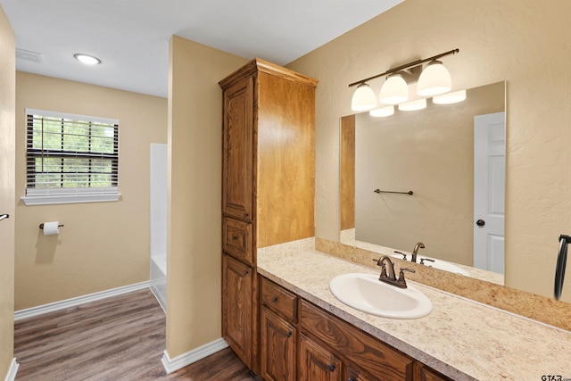 bathroom with vanity, baseboards, a bathing tub, and wood finished floors