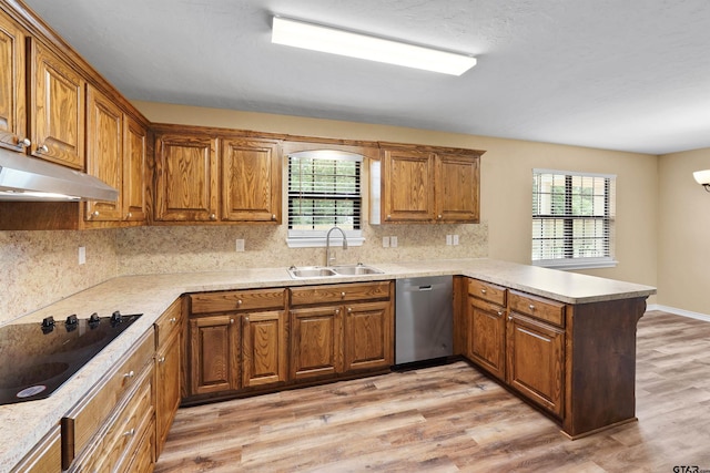 kitchen featuring stainless steel dishwasher, black electric cooktop, a sink, light wood finished floors, and a peninsula