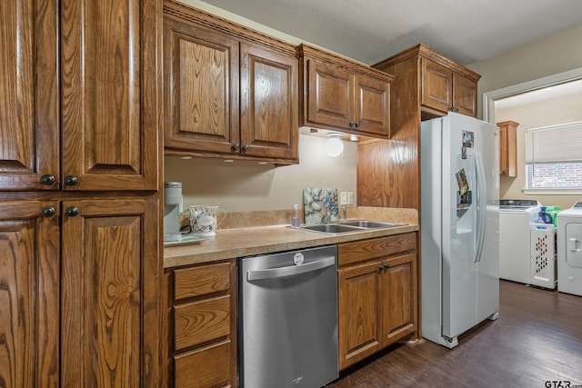 kitchen featuring dishwasher, separate washer and dryer, white fridge with ice dispenser, brown cabinetry, and a sink