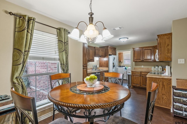 dining room with baseboards, visible vents, dark wood-style flooring, a notable chandelier, and independent washer and dryer