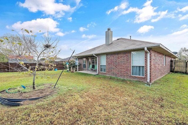 back of house with a patio, a lawn, brick siding, and a fenced backyard