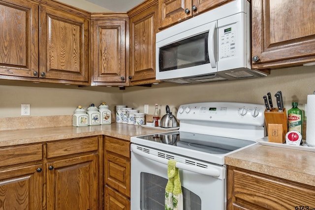 kitchen with white appliances, brown cabinets, and light countertops