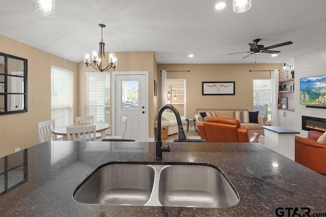 17127 Meadowview Ln, Lindale, TX 75771 - kitchen with a chandelier, a large fireplace, dark stone counters, ceiling fan, and recessed lighting
