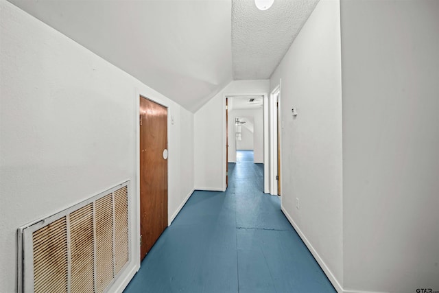 hall with lofted ceiling and a textured ceiling