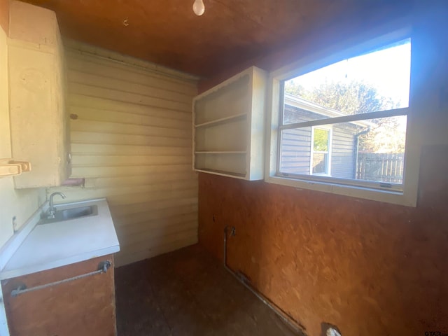 laundry area featuring wood walls and sink