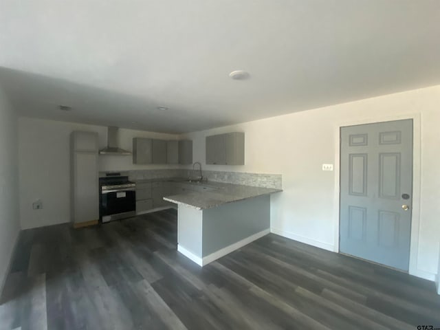 kitchen featuring dark wood-type flooring, kitchen peninsula, wall chimney exhaust hood, and gas range