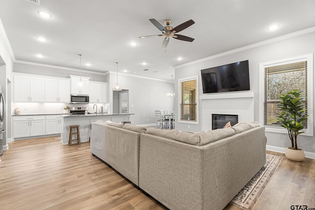 living area with recessed lighting, light wood-type flooring, a glass covered fireplace, and baseboards