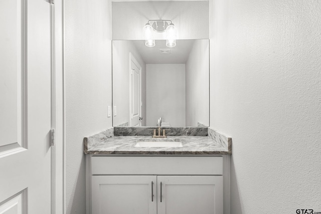 bathroom featuring a textured wall and vanity