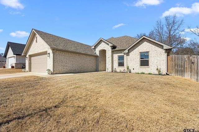 single story home with a garage, a shingled roof, fence, driveway, and a front yard