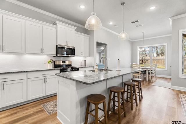 kitchen with visible vents, decorative backsplash, white cabinets, appliances with stainless steel finishes, and a sink