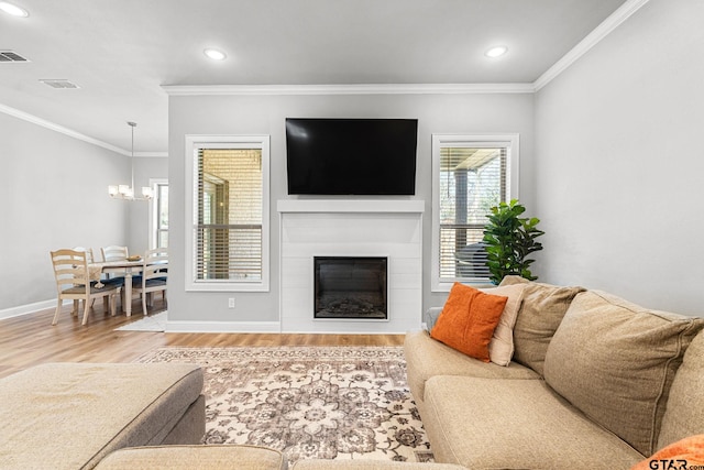 living room with baseboards, a glass covered fireplace, ornamental molding, wood finished floors, and recessed lighting