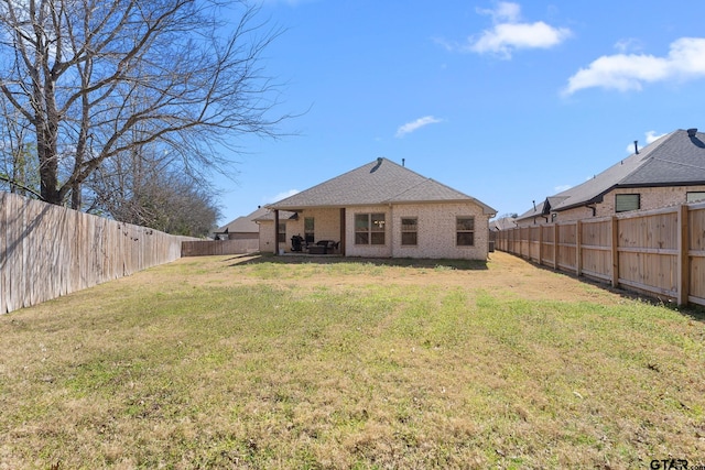 back of property featuring a fenced backyard, a lawn, and brick siding