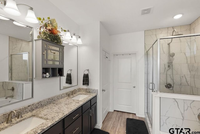 bathroom with visible vents, a shower stall, double vanity, and a sink